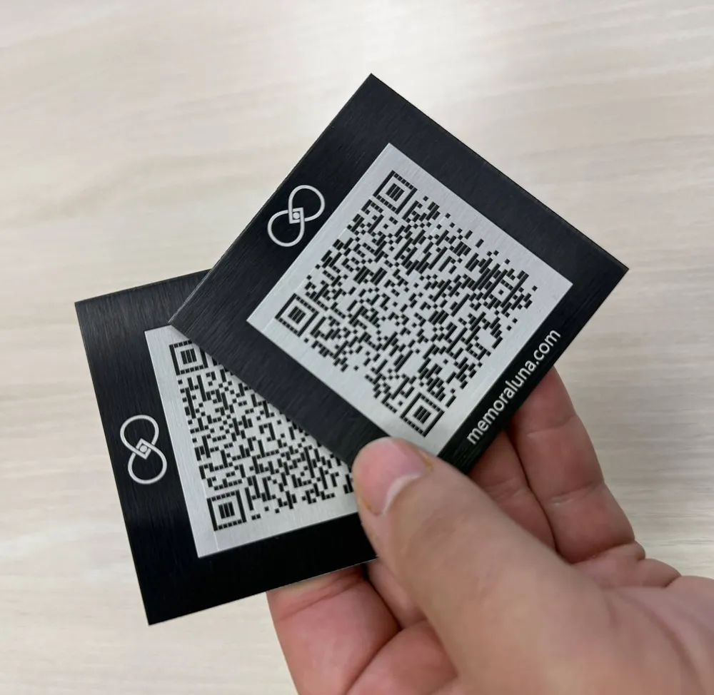 Deux plaques commémoratives QR code Memoraluna tenues dans une main