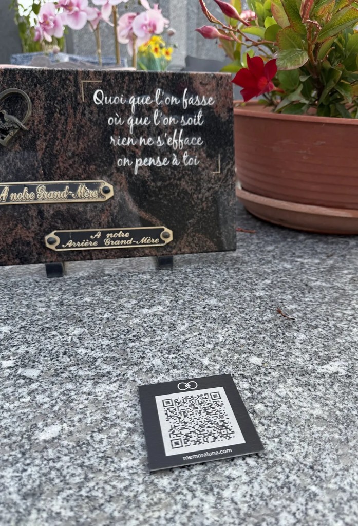 Une plaque QR Memoraluna posée devant une stèle en granit.
